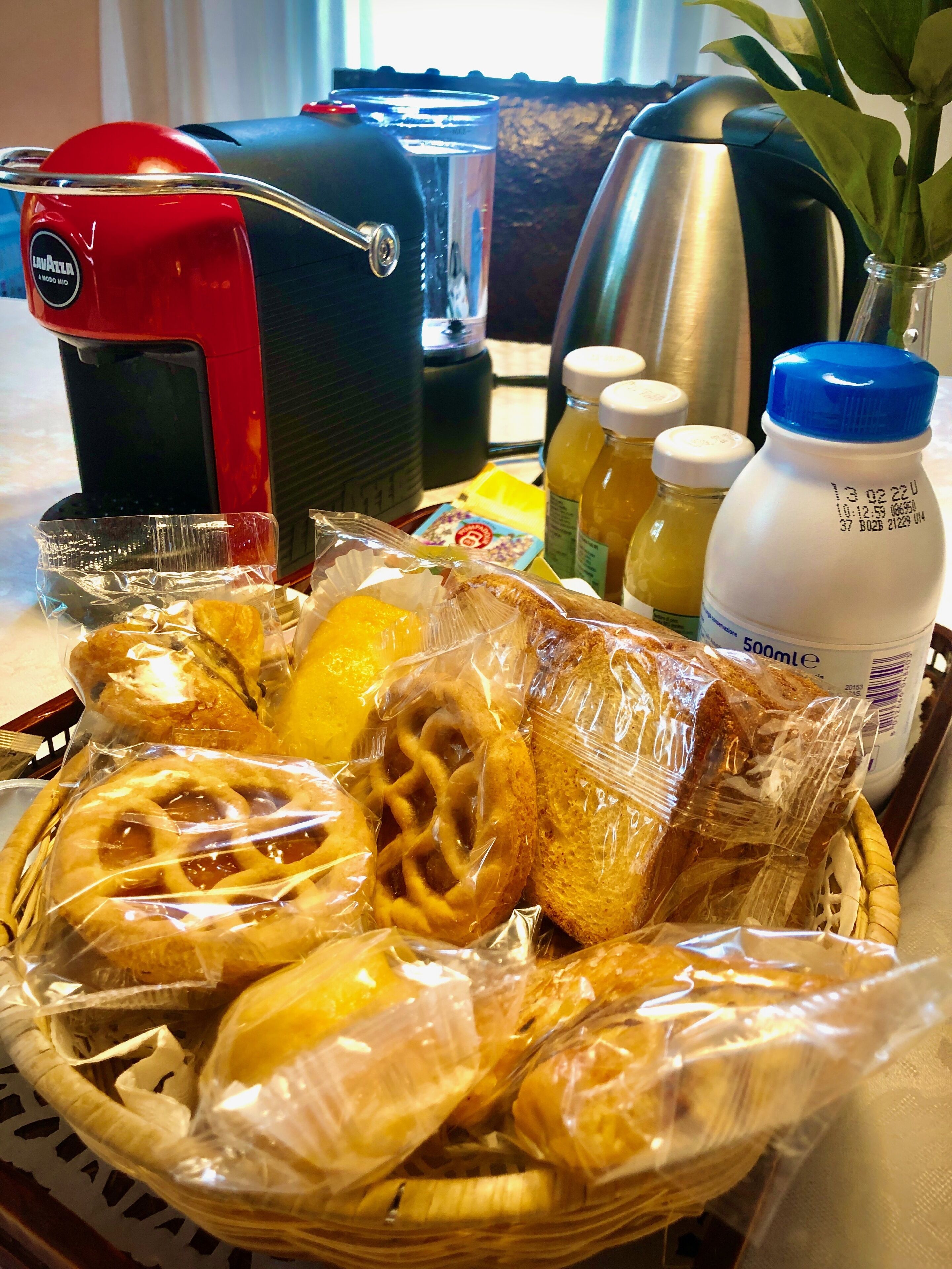 A breakfast tray with pastries, a coffee maker, a kettle, and juice bottles.