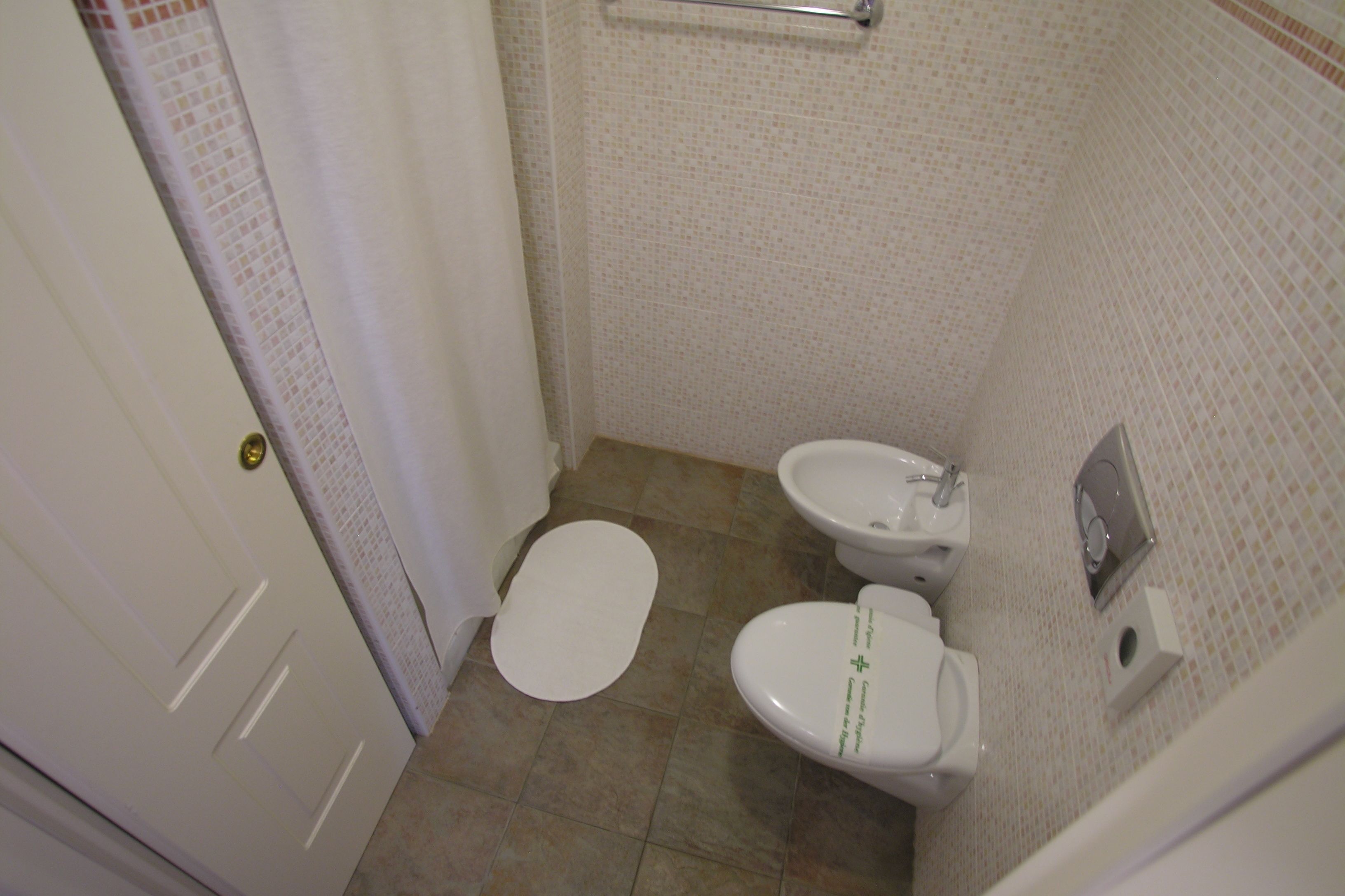 A small bathroom with a toilet, bidet, and a towel rack.