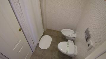A small bathroom with a toilet, bidet, and a towel rack.