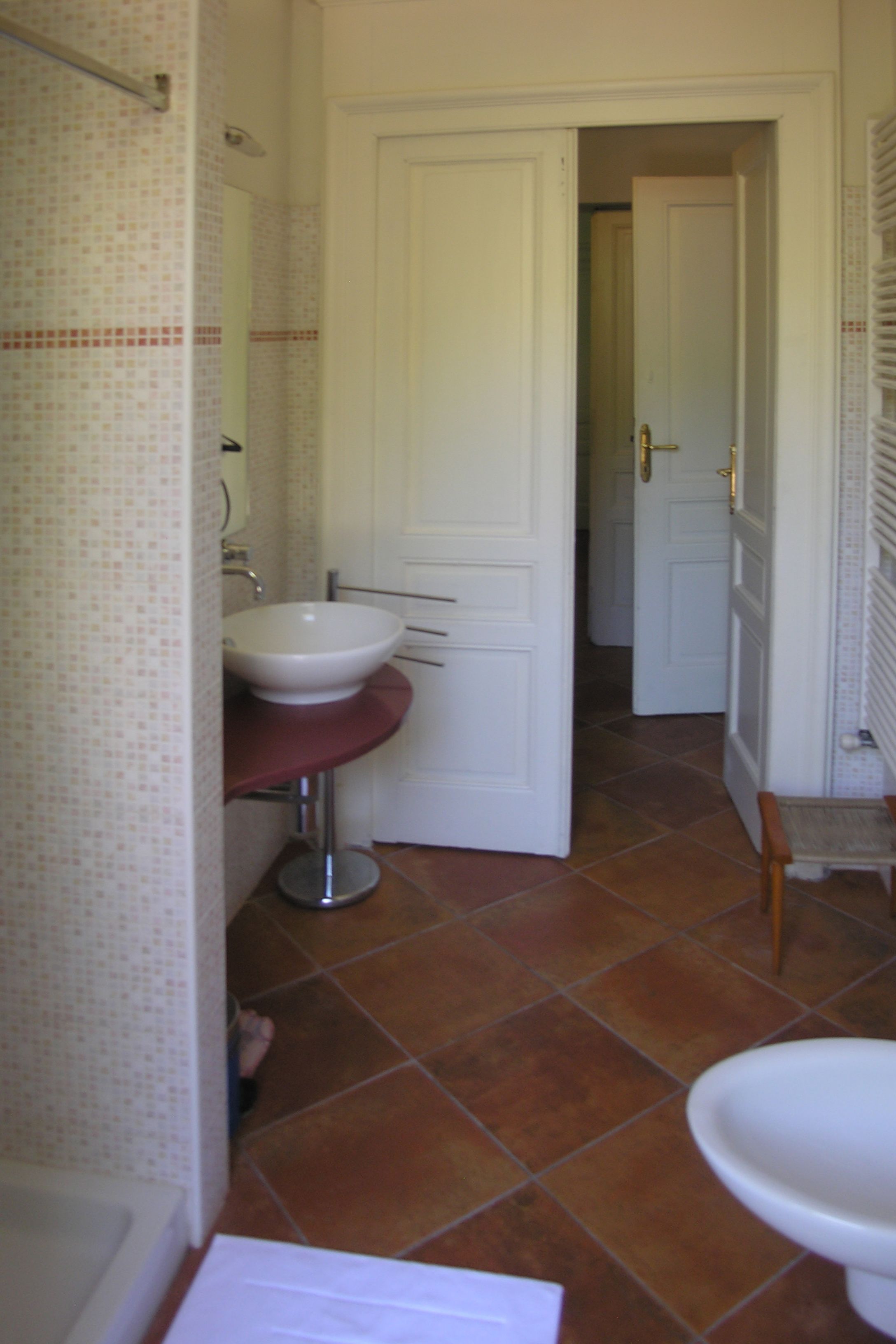 A bathroom with a white sink, a mirror, and a door leading to another room.