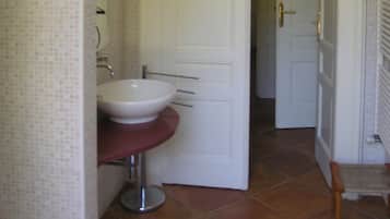A bathroom with a white sink, a mirror, and a door leading to another room.