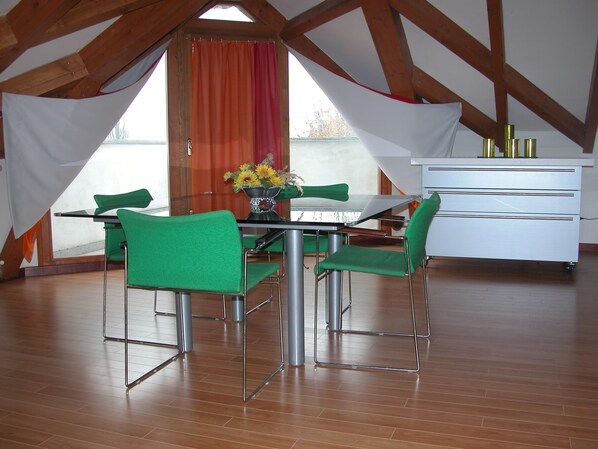 A dining area with a table and chairs, a white cabinet, and a window with curtains. - Villa D'Azeglio (Albiano d'Ivrea)