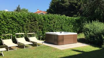 A hot tub with two lounge chairs in a garden.
