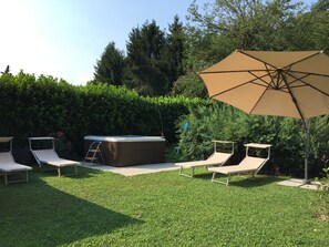 Relax in style with a hot tub and lounge chairs surrounded by a beautifully manicured hedge.