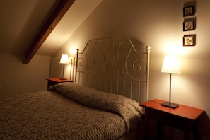Cozy bedroom with a sloped ceiling, featuring a bed and two bedside tables with lamps.