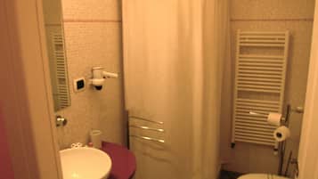 A small bathroom with a shower curtain, a sink, a toilet, and a bidet.