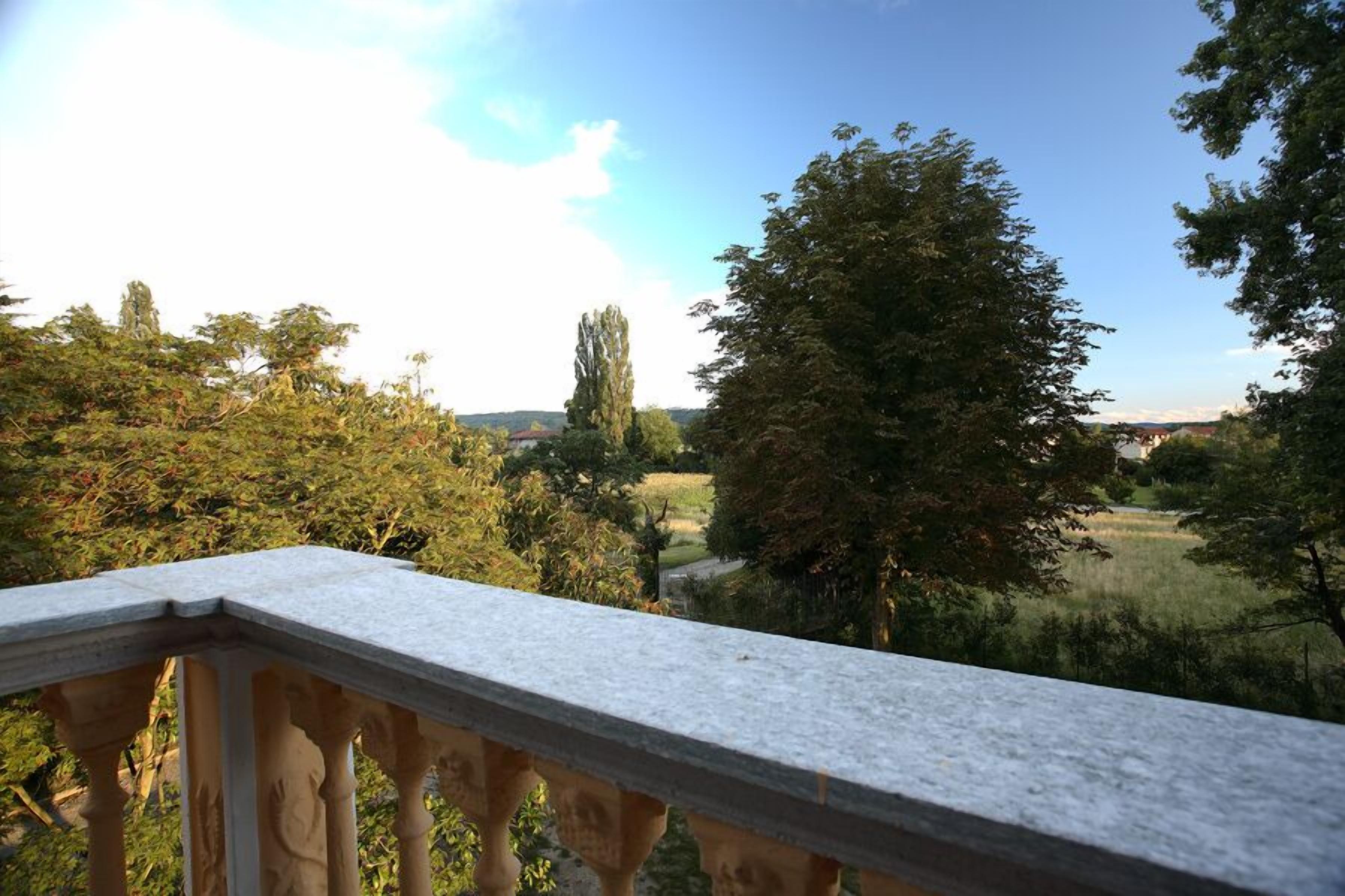 Uma varanda com vista para um campo gramado e árvores.