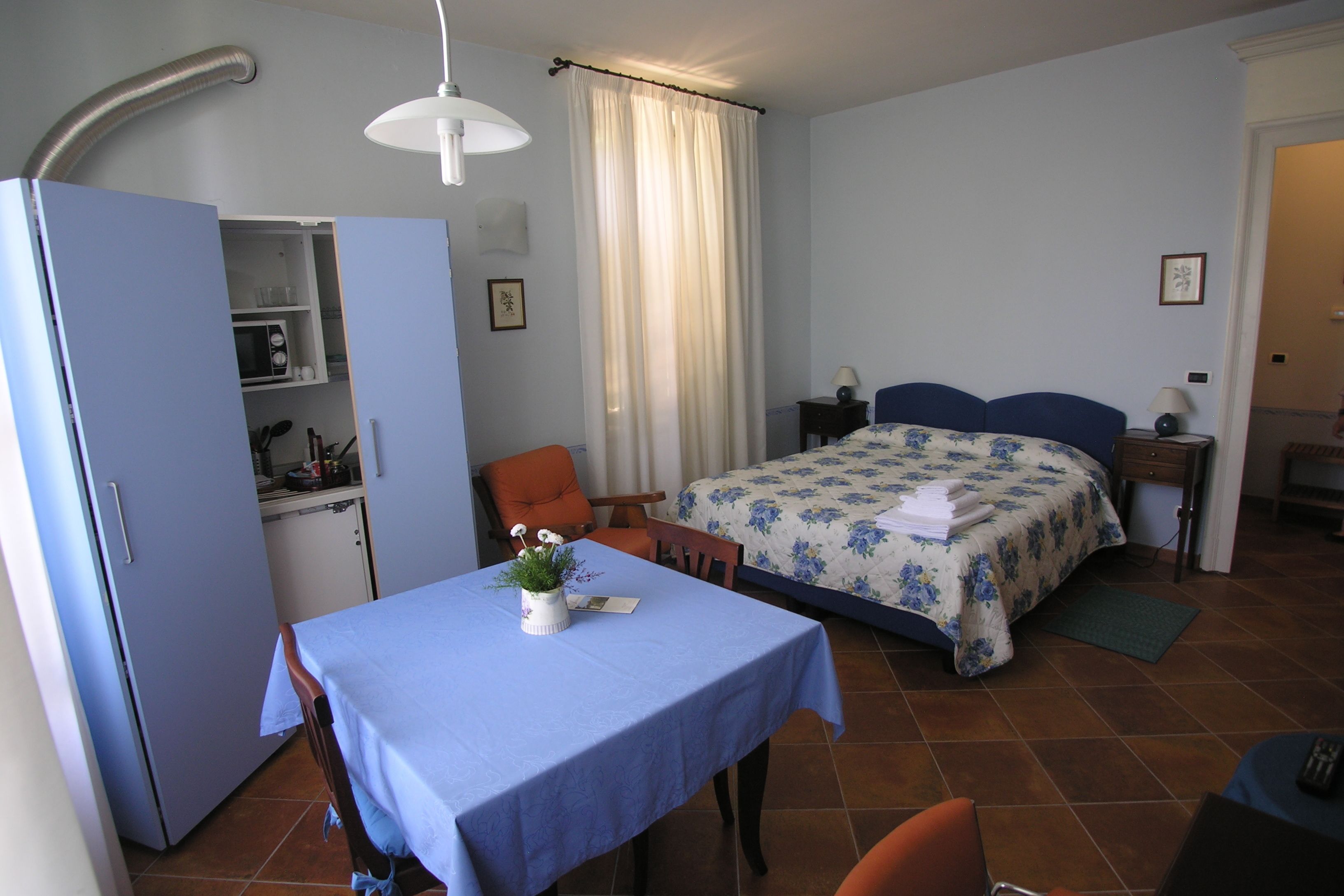 Un dormitorio pequeño con cama, mesita de noche y una pequeña mesa con una planta.