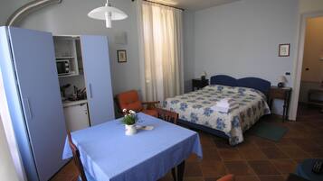 Un dormitorio pequeño con cama, mesita de noche y una pequeña mesa con una planta.