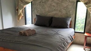 A bedroom with a wooden bed frame, grey bedding, and a view through a window. - Poopreaw Resort (Koh Lan)