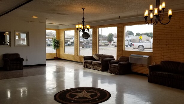 A spacious lobby with a polished concrete floor, a large star-patterned rug, and several upholstered chairs. - Americas Premier Inn (Sweetwater)