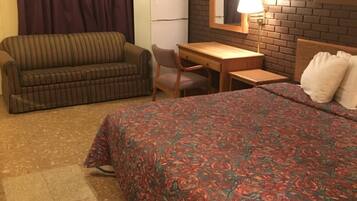 A room with a bed, a sofa, a desk, and a refrigerator.