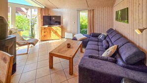 A modern living room with a wooden ceiling, a large sectional sofa, a wooden coffee table, a television, and a fireplace. - Nice home in Rechlin with sauna (Rechlin)