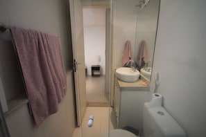 Un baño con inodoro, lavamanos y una toalla colgada en la pared.