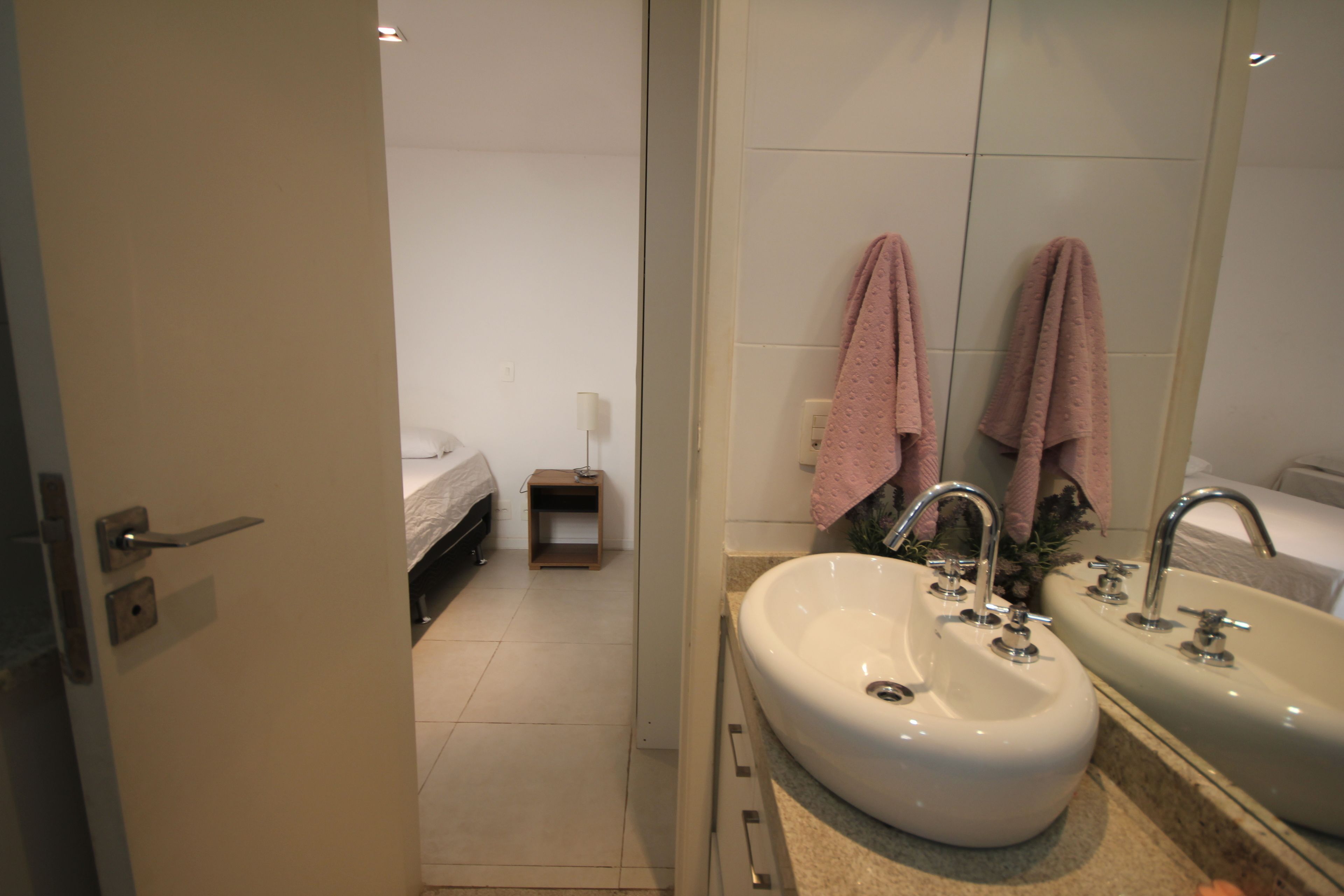Un baño moderno con lavamanos doble, un espejo y dos toallas colgadas en la pared.