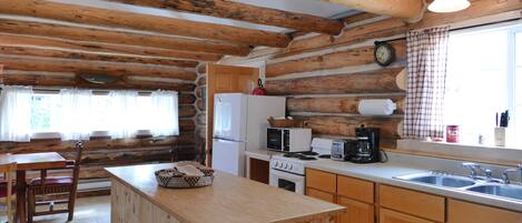 Una cucina in stile rustico con travi in legno, un'isola di legno, un lavello ed elettrodomestici essenziali.
