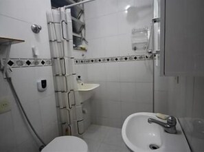 A small, compact bathroom with a toilet, sink, and shower area.