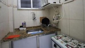 Una pequeña cocina con un lavabo, una ventana y un microondas.
