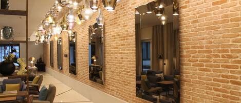A spacious lobby with a brick wall, multiple seating areas, and a variety of hanging pendant lights.