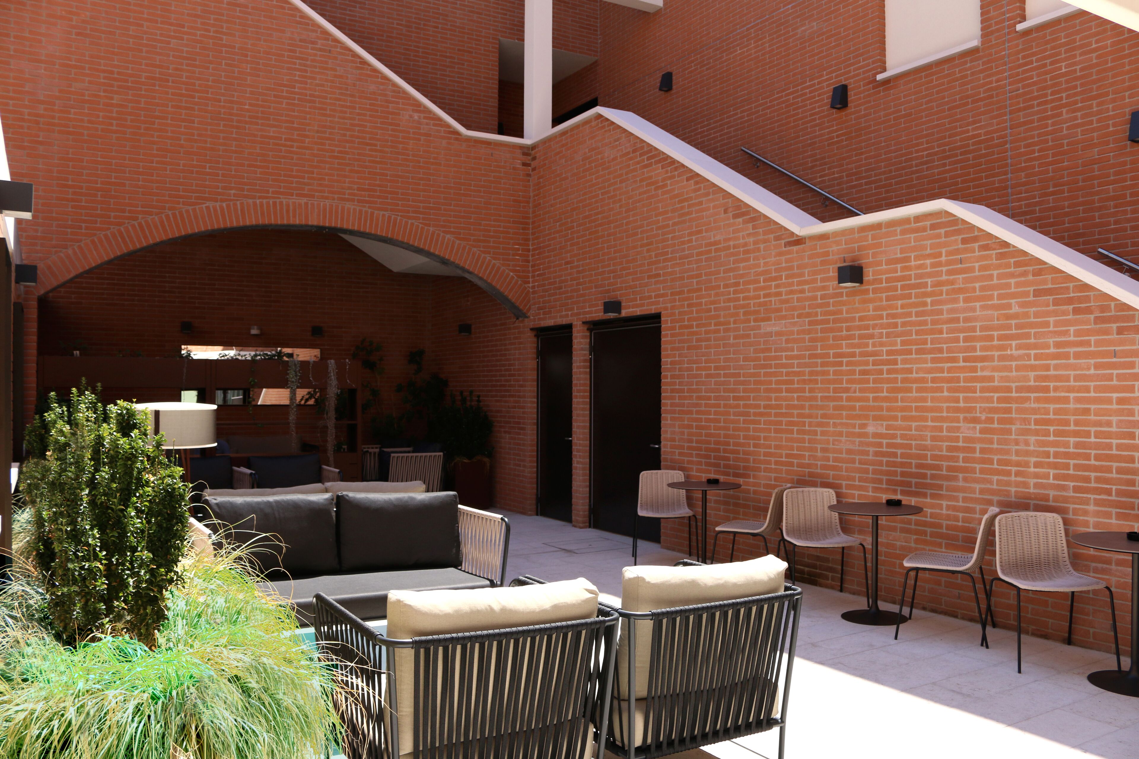 An outdoor patio area with brick walls, a staircase, and seating arrangements including sofas and chairs.