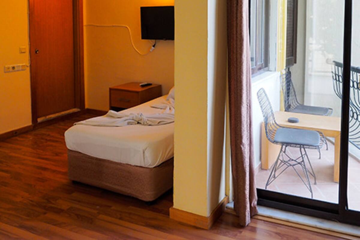 Ein Hotelzimmer mit Bett, Nachttisch, Fernseher und Blick auf einen Balkon.