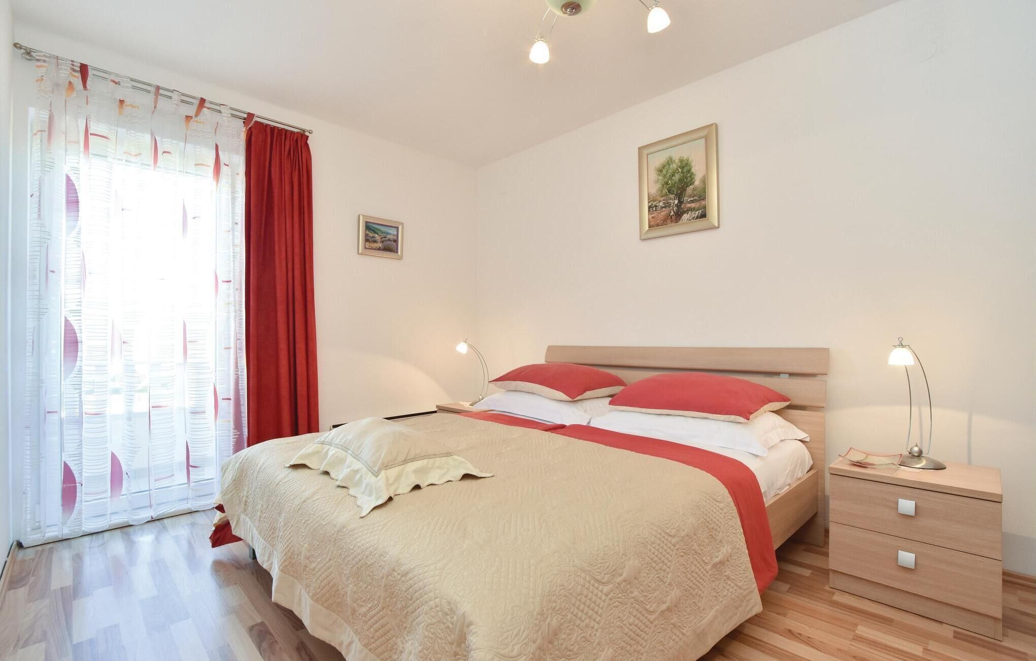 A neatly arranged bedroom with a bed, bedside tables, and a window with curtains.