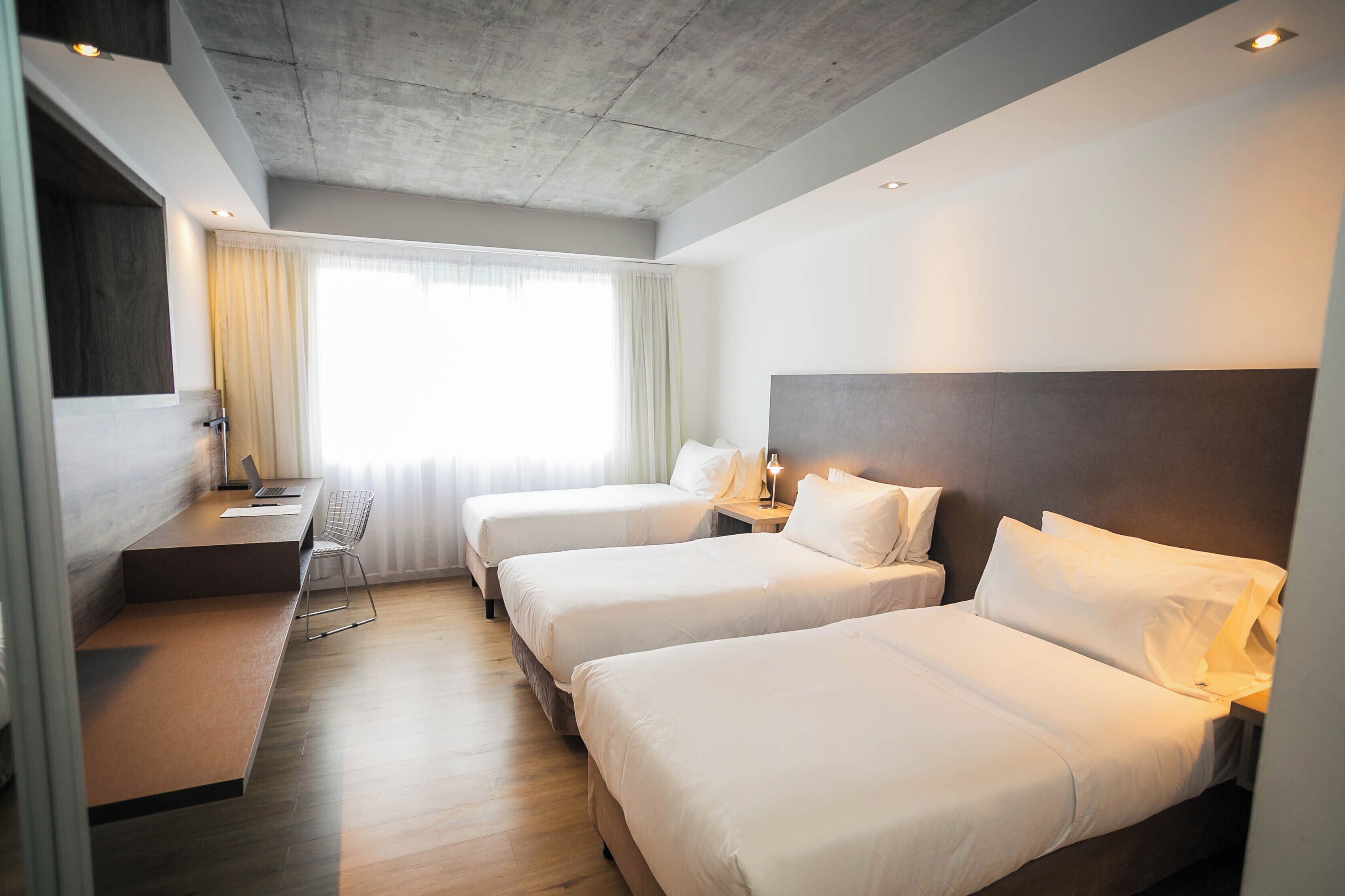 A hotel room with two beds, a desk, and a chair.