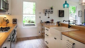 Una cocina moderna con un amplio ventanal, armarios de madera y una campana extractora de acero inoxidable.