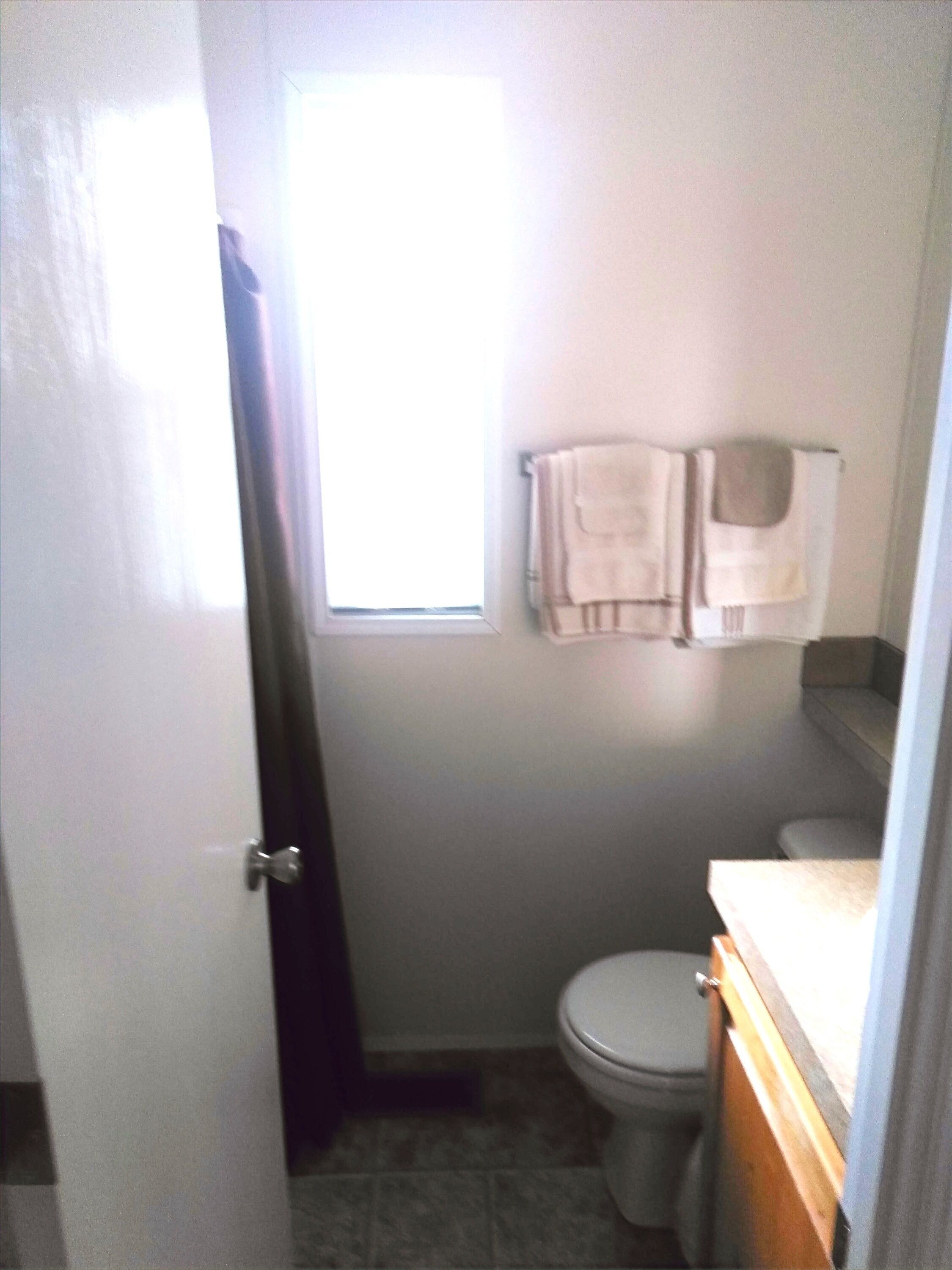 Une petite salle de bain avec des toilettes, un lavabo et une fenêtre.