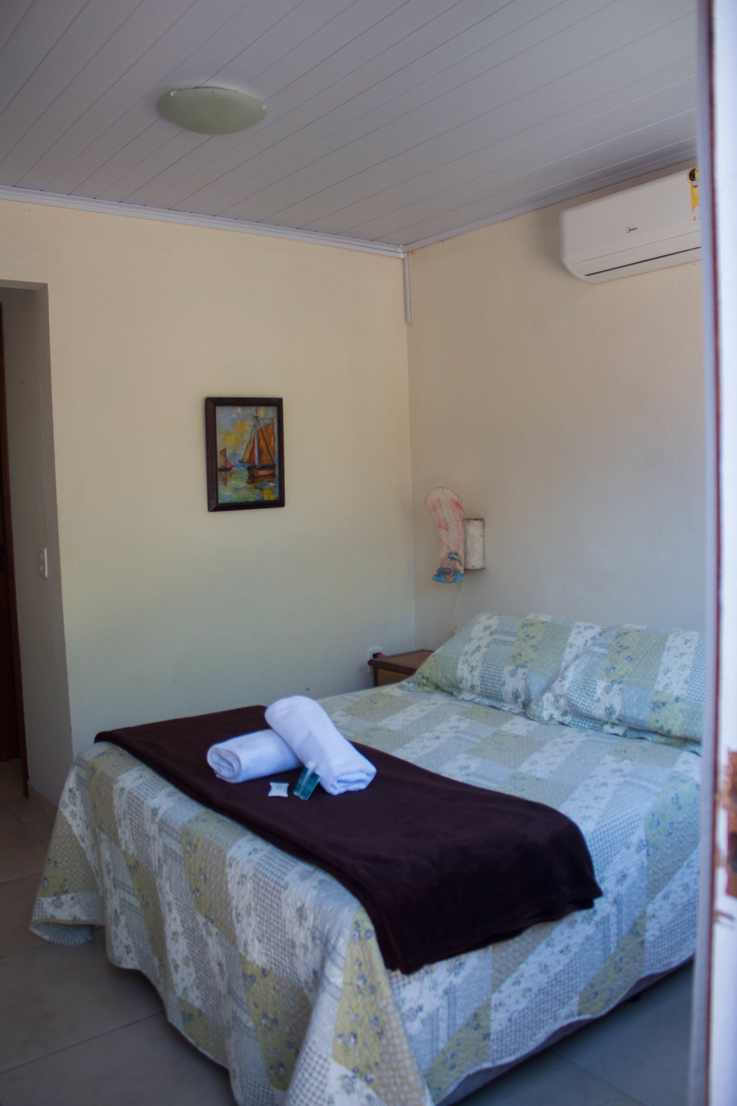 Ein Schlafzimmer mit Bett, einem Gemälde, einer Klimaanlage und einer Tür.