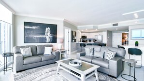 A modern living room with grey sofas, a coffee table, and a large abstract painting. - Seaside charm in beachfront condo w/private balcony & beach service in Destin! (Destin)