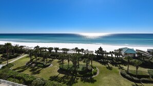 A beachfront property with a well-maintained lawn, palm trees, and a view of the ocean. - Seaside charm in beachfront condo w/private balcony & beach service in Destin! (Destin)