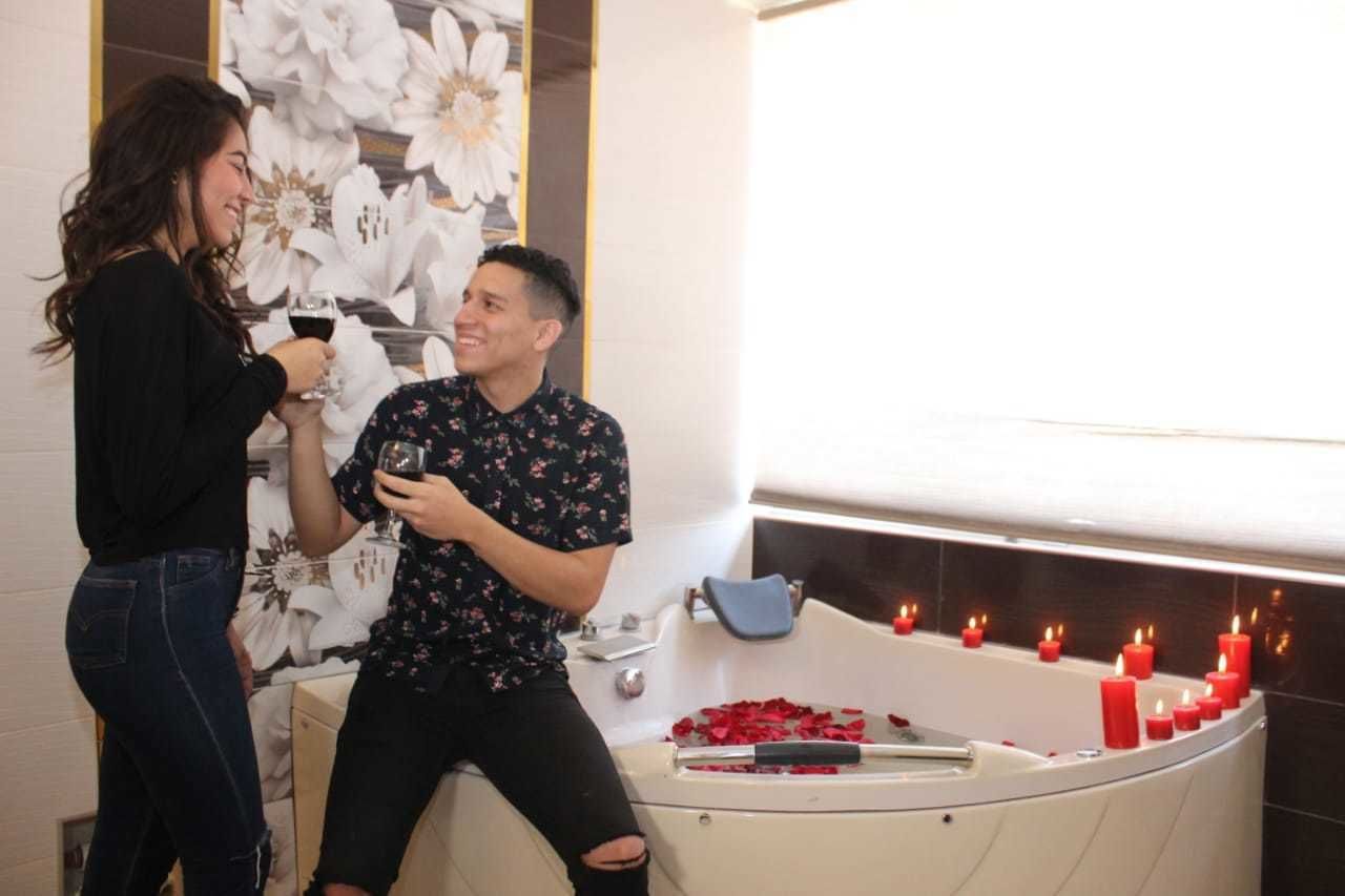 Ein Mann und eine Frau in einem Badezimmer mit Badewanne, Kerzen und Rosenblättern.