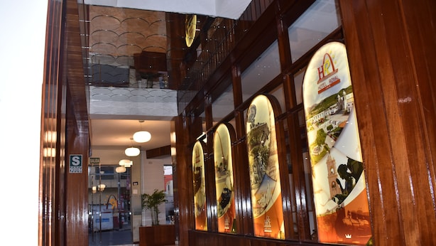 Entrada de hotel con piso pulido, mostrador de recepción y señalización de salida.
