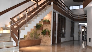 Un interior espacioso con una escalera de mármol pulido, detalles de madera y jardineras integradas.