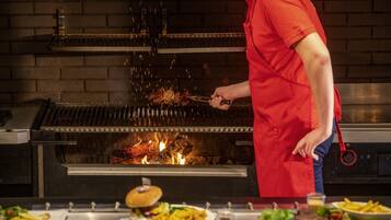 A chef grilling meat on a large grill in a kitchen.