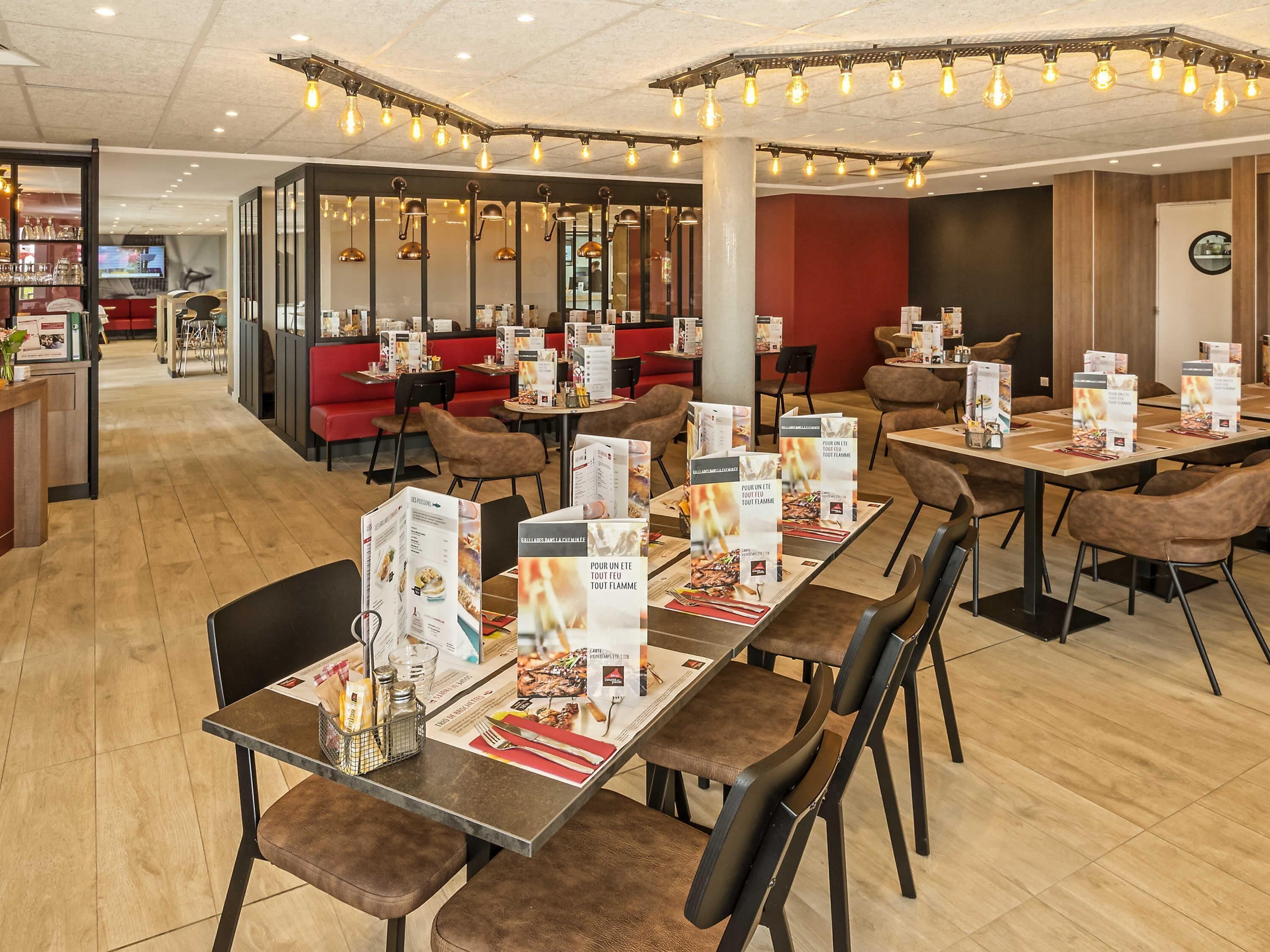 A restaurant with tables set for dining, menus, and a bar area in the background.