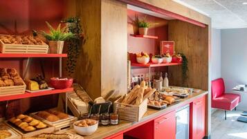 Un buffet de petit-déjeuner proposant un assortiment de pains, de viennoiseries et de fruits.