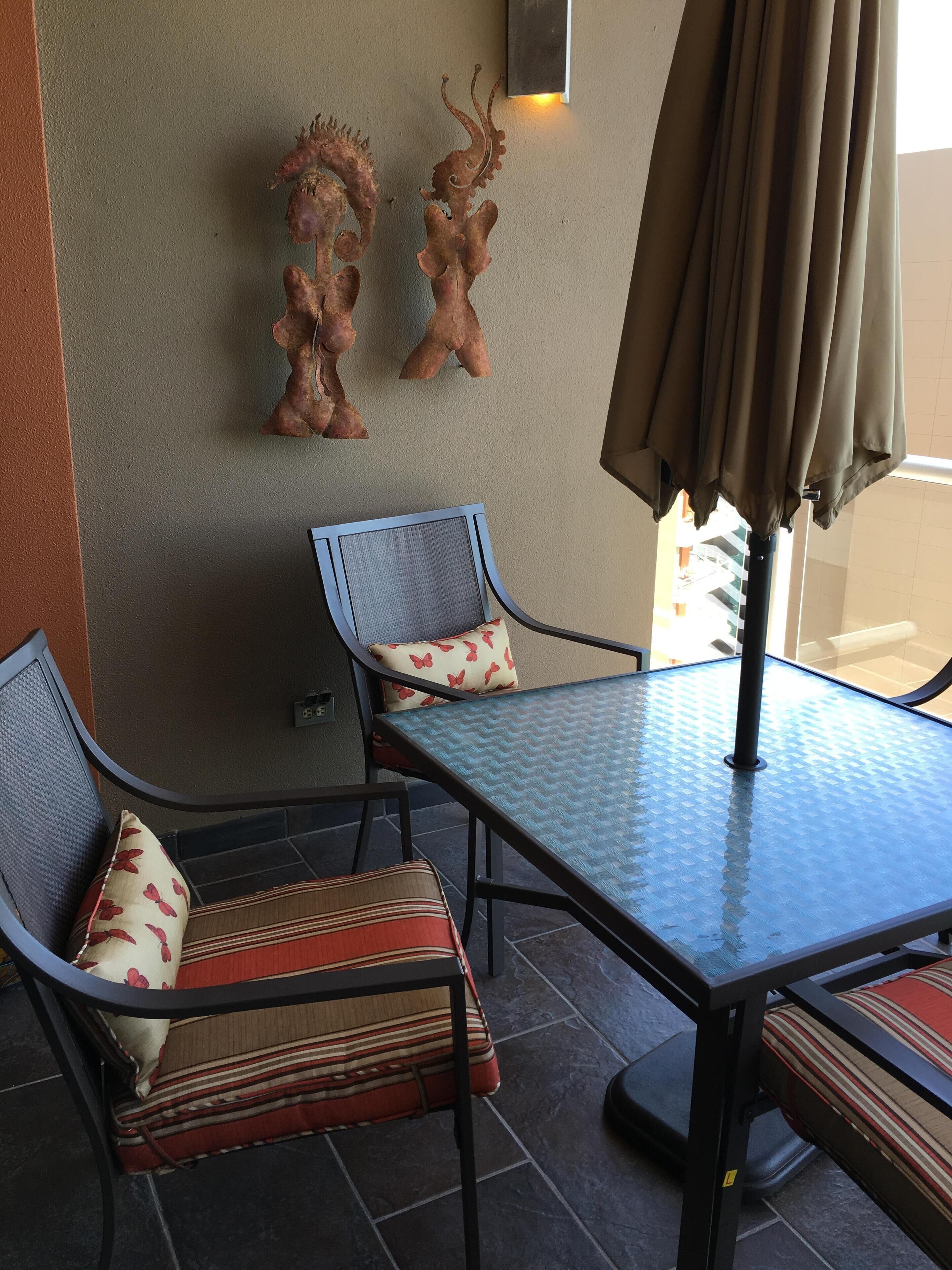 Un espace patio aménagé avec une table et deux chaises, un mur décoratif et un parasol.