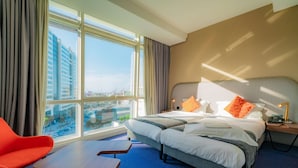 A hotel room with a large window, a bed with multiple pillows, a bedside table with a lamp, and a red chair. - Hotel Campanile Casablanca Centre Ville (Casablanca)