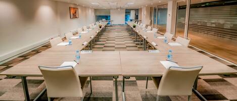 Un salón de conferencias con una larga mesa, sillas y una pantalla para proyector.