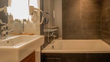 Ein modernes Badezimmer mit einer großen Badewanne, einem Waschtisch inklusive Spiegel und einer separaten Duschkabine.