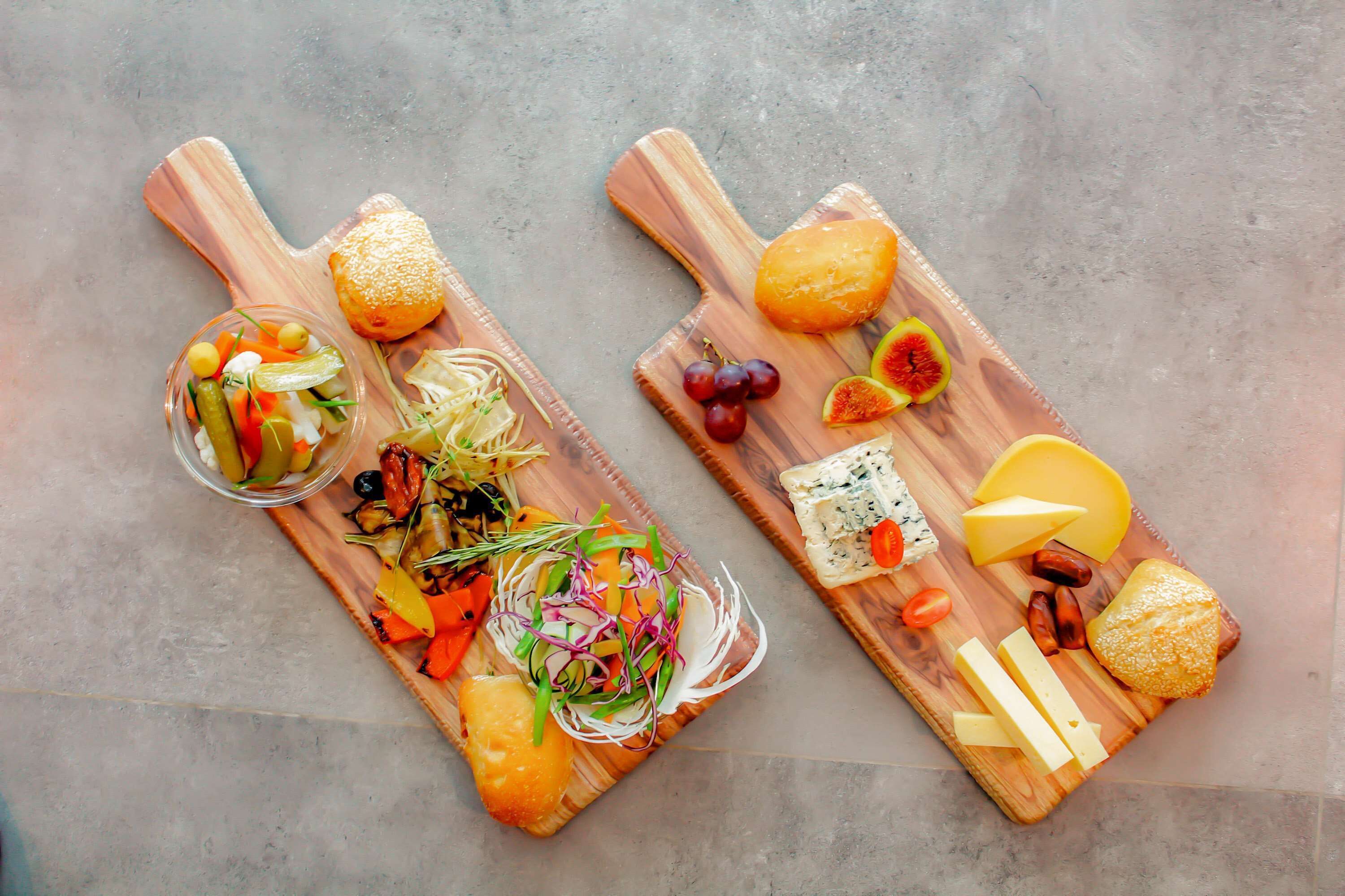 Two wooden serving boards with various food items and a glass bowl of mixed vegetables.