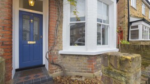 A traditional house with a blue door, a white window, and a stone base. - Traditional Home in Kew Gardens (Richmond)