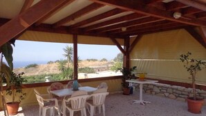 An outdoor patio with a table and chairs, a view of the sea, and potted plants. -  exceptional holidays  (Gouvès Hersonissos Crête Grèce)