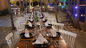 An outdoor dining area with tables set for a meal, surrounded by trees and string lights. - Sunsol Ecoland (Matasiete)