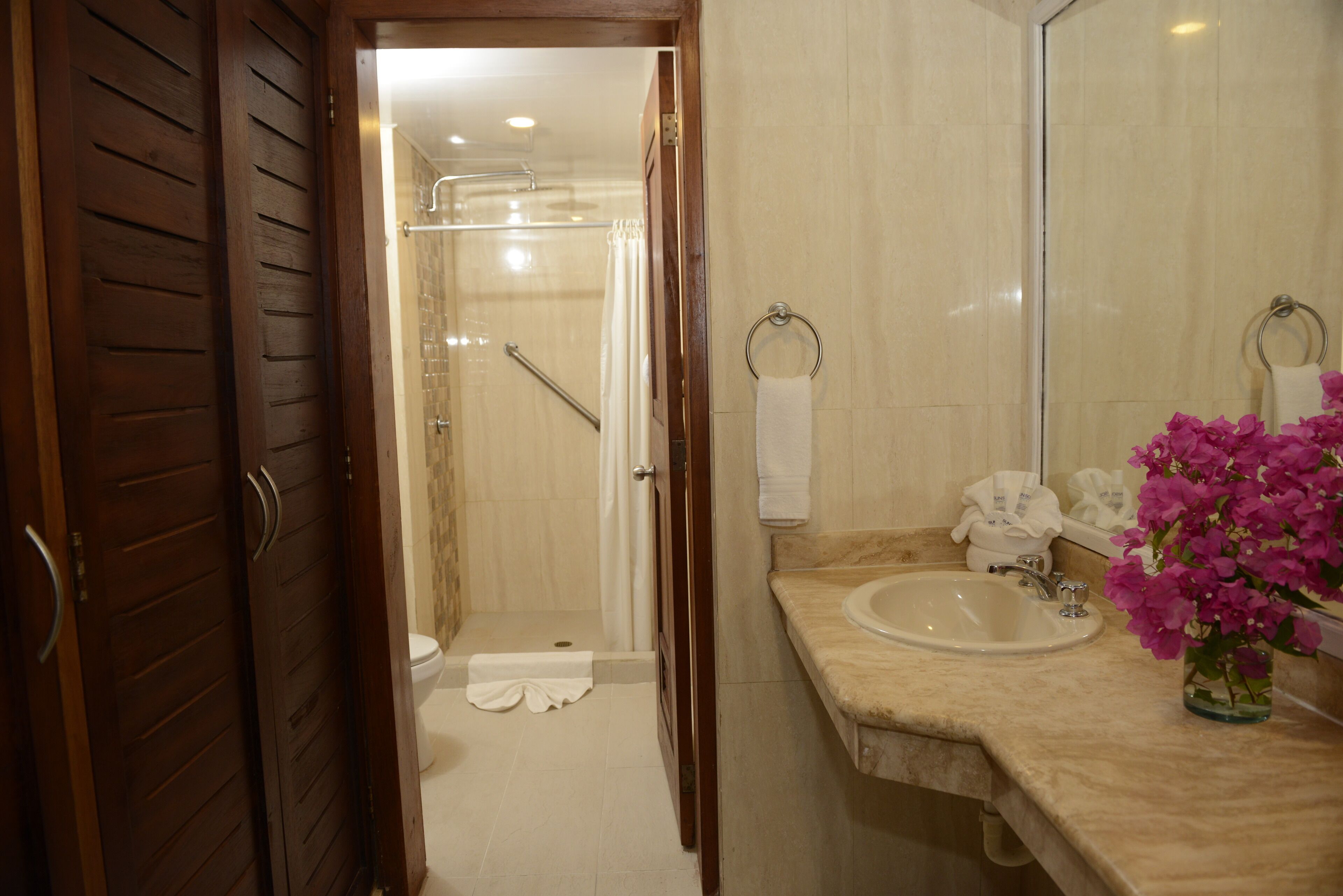 Een badkamer met een douche, wastafel en spiegel.