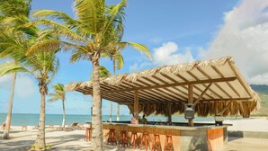 A beach bar with a thatched roof, wooden stools, and a view of the ocean. - Sunsol Ecoland (Matasiete)