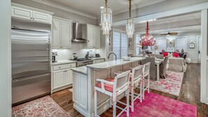 A modern kitchen with stainless steel appliances, a central island with bar stools, and a chandelier. - WaterColor Home with 6-Passenger Electric Cart, 4 Bikes & Beach Club Access (Seagrove Beach)