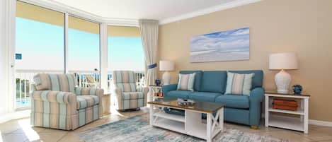 A living room with a sofa, armchairs, a coffee table, and a view of the outdoors.